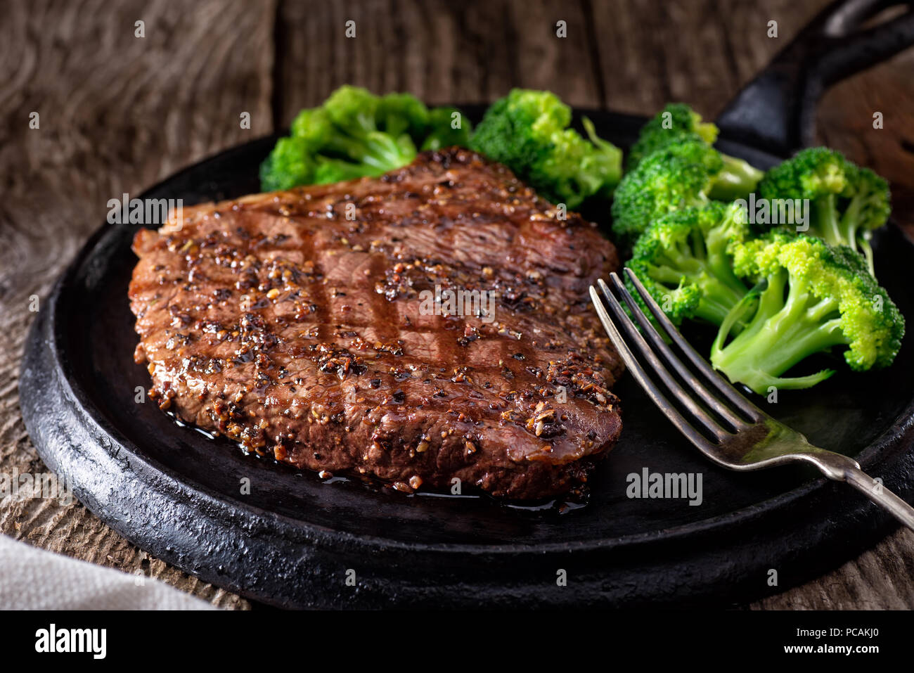 Una deliziosa grigliata di Bistecca al pepe con broccoli su una tavola in legno rustico. Foto Stock