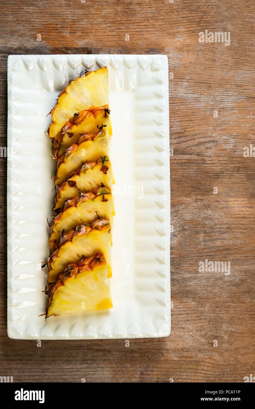 Ananas frutta tagliata a spicchi su piastra di sfondo di legno snack sani Foto Stock
