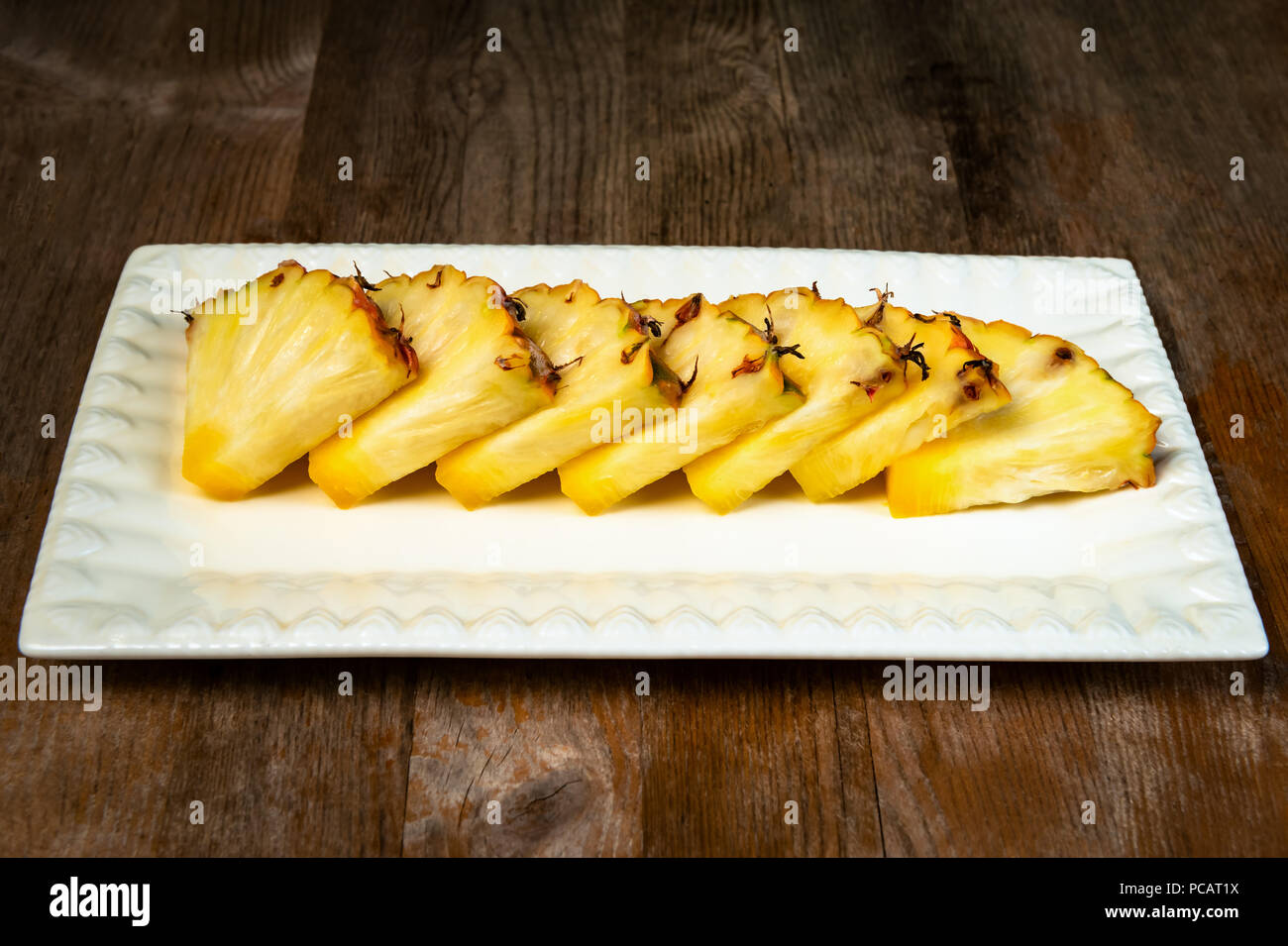 Ananas frutta tagliata a spicchi su piastra di sfondo di legno snack sani Foto Stock
