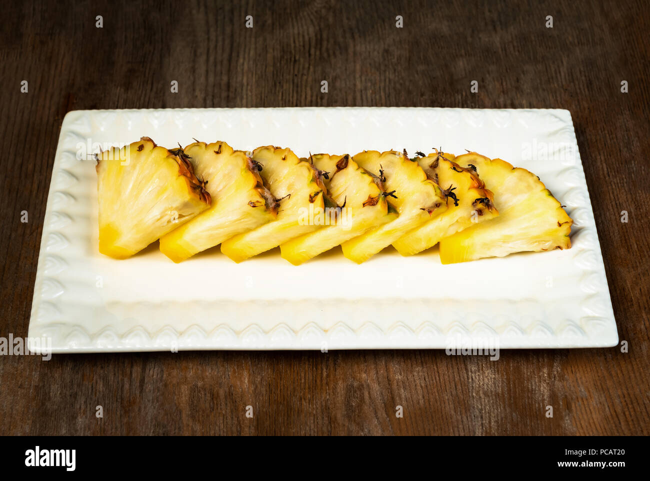 Ananas frutta tagliata a spicchi su piastra di sfondo di legno snack sani Foto Stock