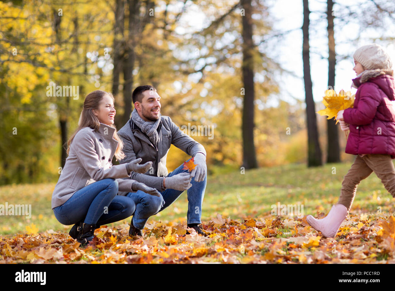 La famiglia felice con foglie di acero in autunno park Foto Stock