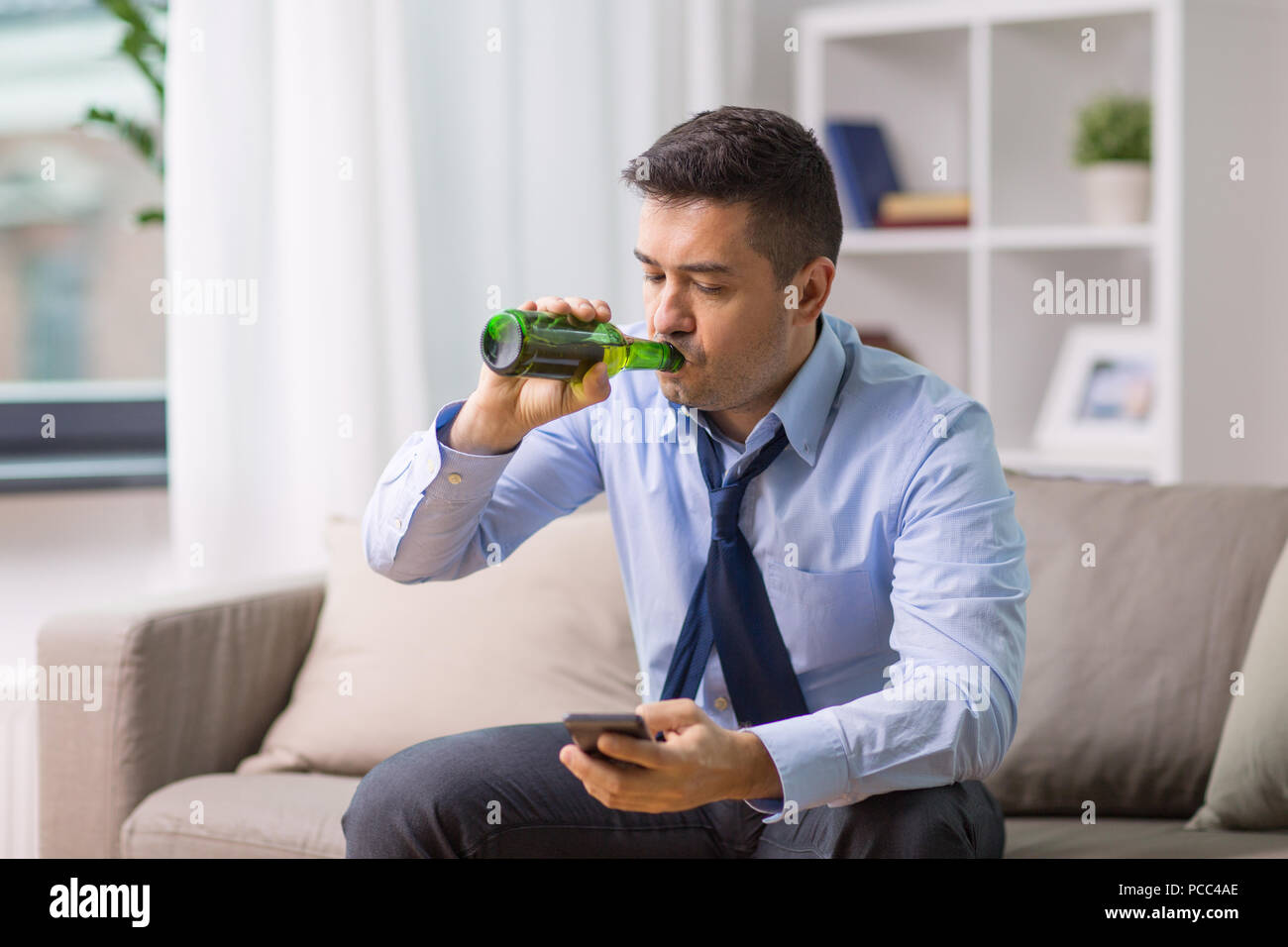 Bevande alcoliche con lo smartphone a bere birra a casa Foto Stock