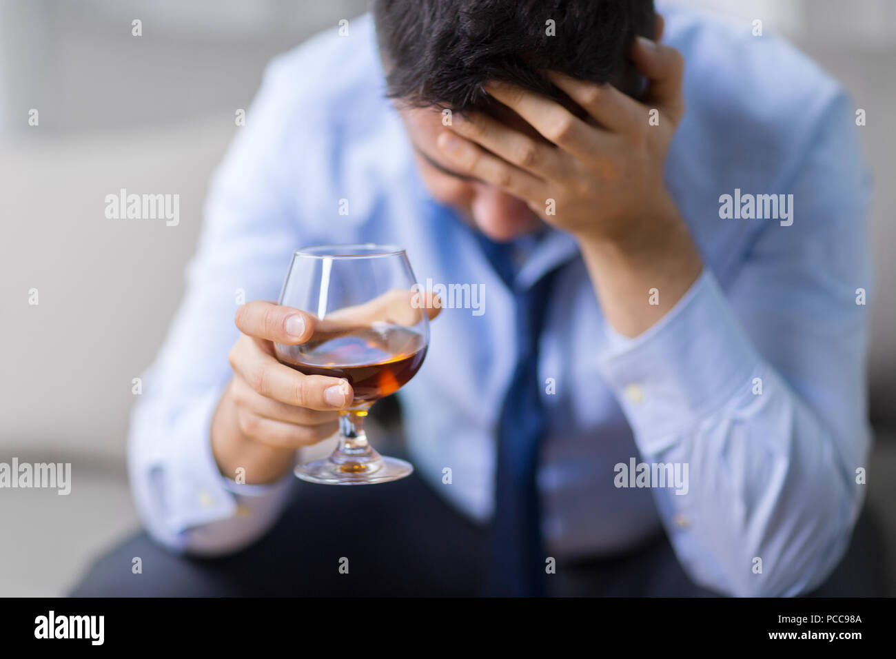 Uomo ubriaco con vetro di alcol a casa Foto Stock