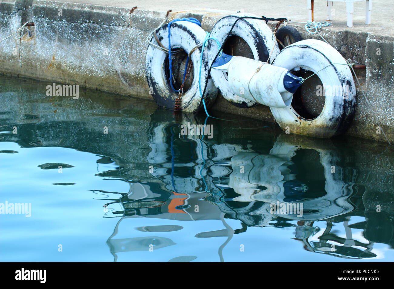 Un riflesso nell'acqua di vecchi pneumatici sul porto di Limenas Thasou, Grecia Foto Stock