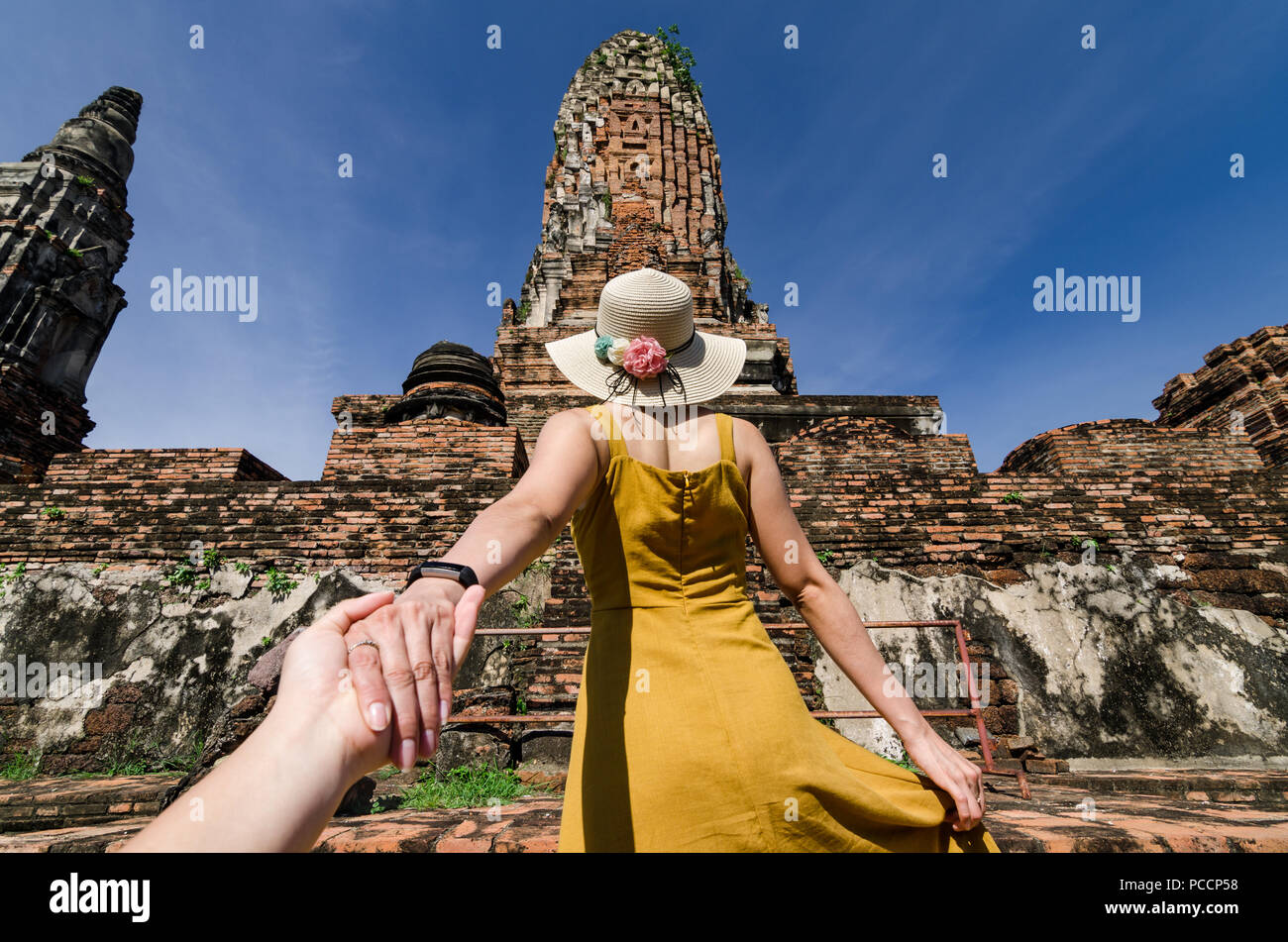 Ritratto di bella ragazza asiatica che conduce il suo partner a mano per il famoso Wat Phra Ram. Il Wat è un tempio buddista in Ayutthaya, Thailandia. Foto Stock