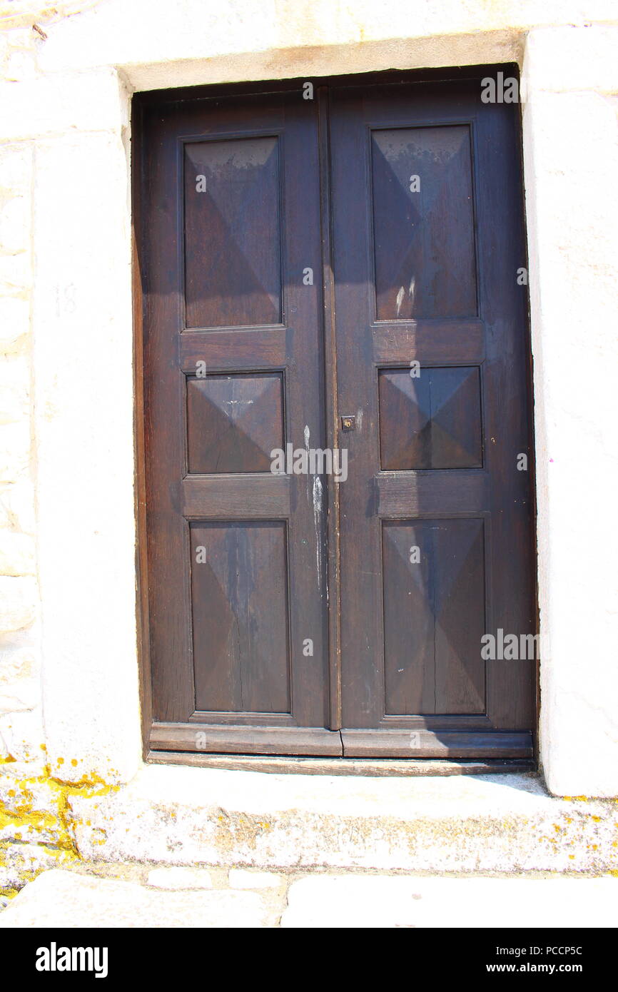 Una porta di legno scuro su un bianco muro di pietra Foto Stock