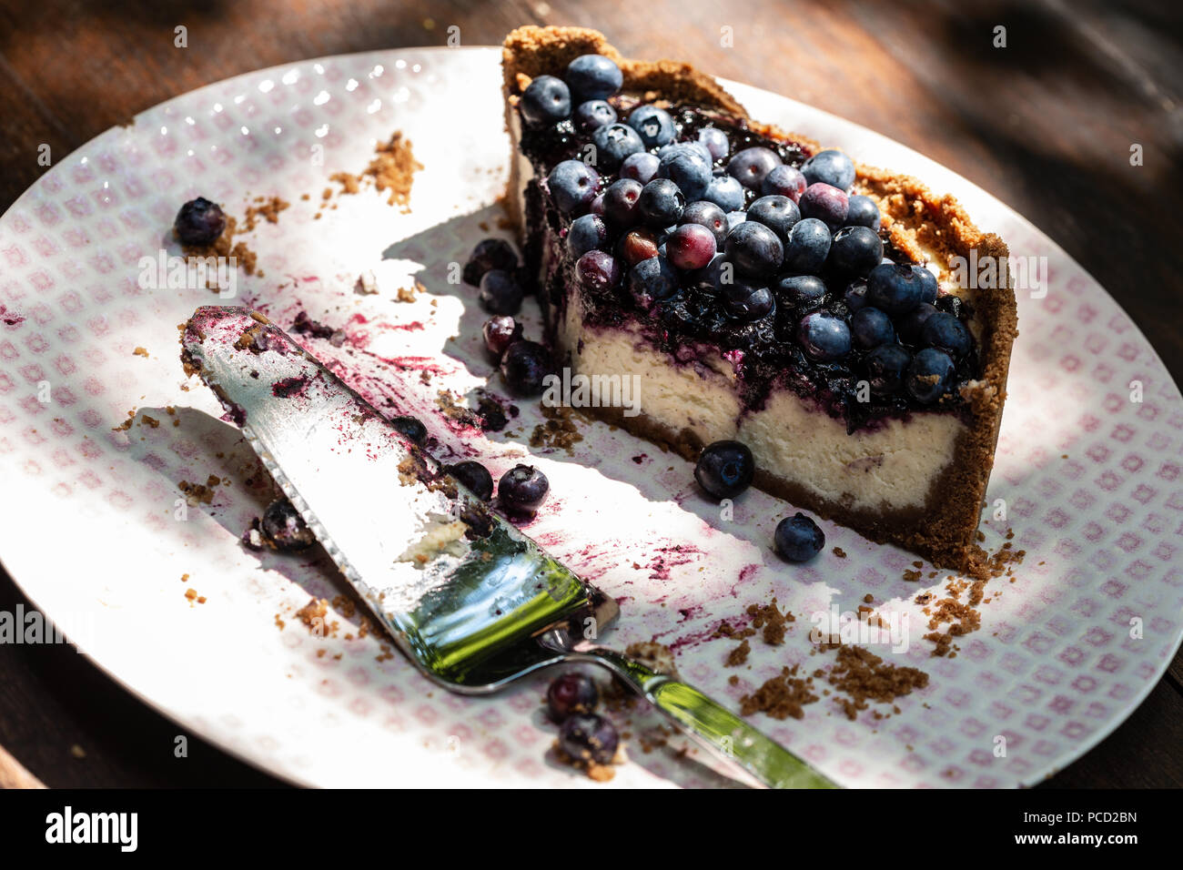 Cheesecake con bluberries sulla cima di una piastra con la fetta di torta Foto Stock