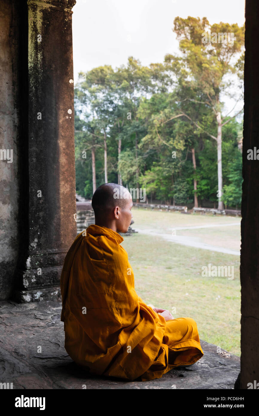 Monaco buddista seduto in un corridoio colonnato in un tempio di Angkor Wat, UNESCO, Siem Reap, Cambogia, Indocina, Asia sud-orientale, Asia Foto Stock