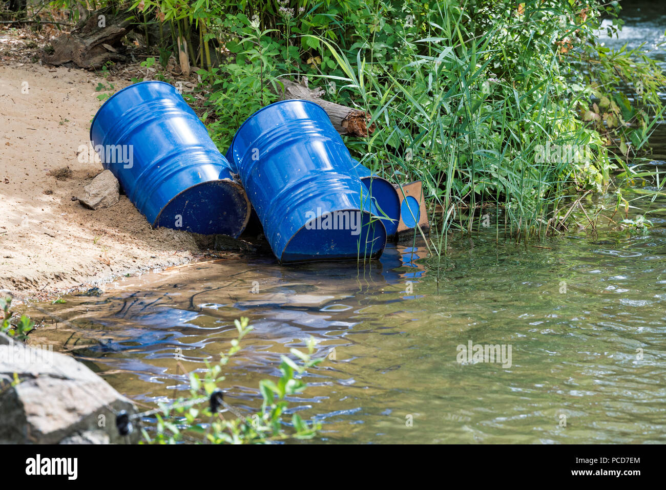 Blu di dumping i fusti di olio causa di inquinamento dell'acqua, più e più l'acqua è inquinata da gettare via i rifiuti che quindi ottiene nei fiumi Foto Stock