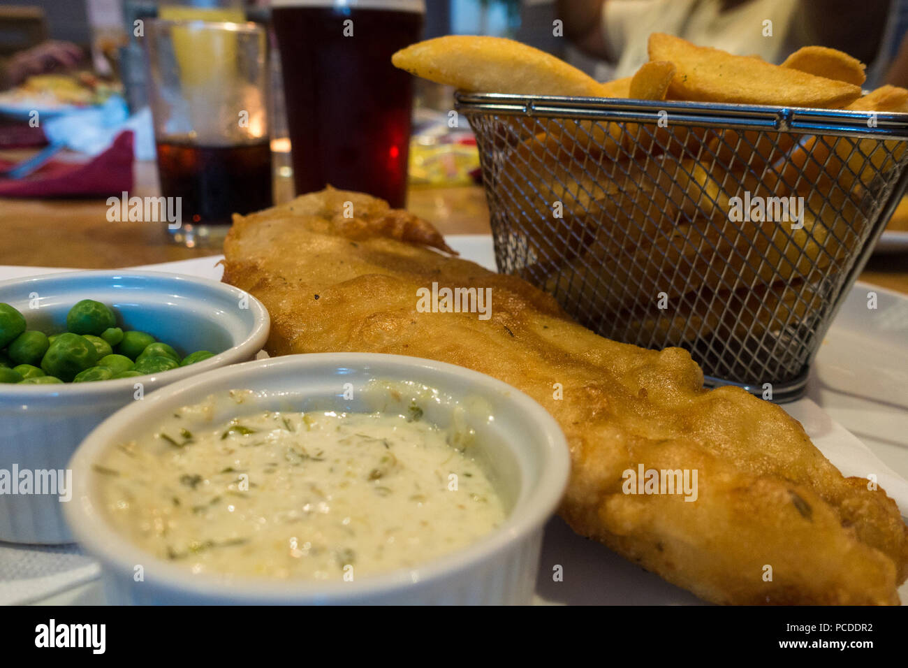 Pesce e patatine fritte in un cestello con giardino di piselli e salsa tartara. Foto Stock