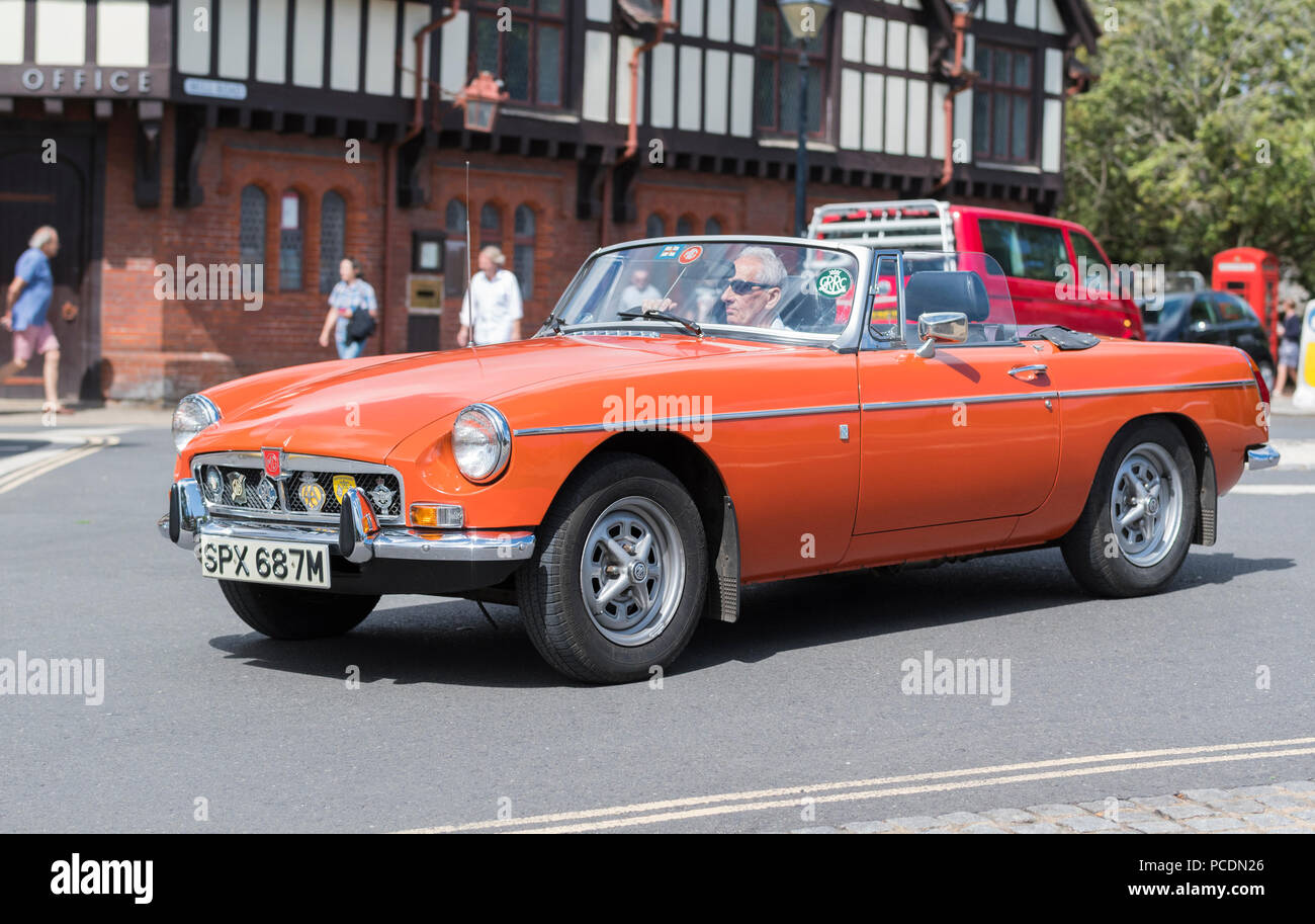Orange BMC MG B (MGB) piccolo coupé 2 porte sport convertibile auto dal 1974 con la parte superiore verso il basso in estate nel West Sussex, in Inghilterra, Regno Unito. Foto Stock