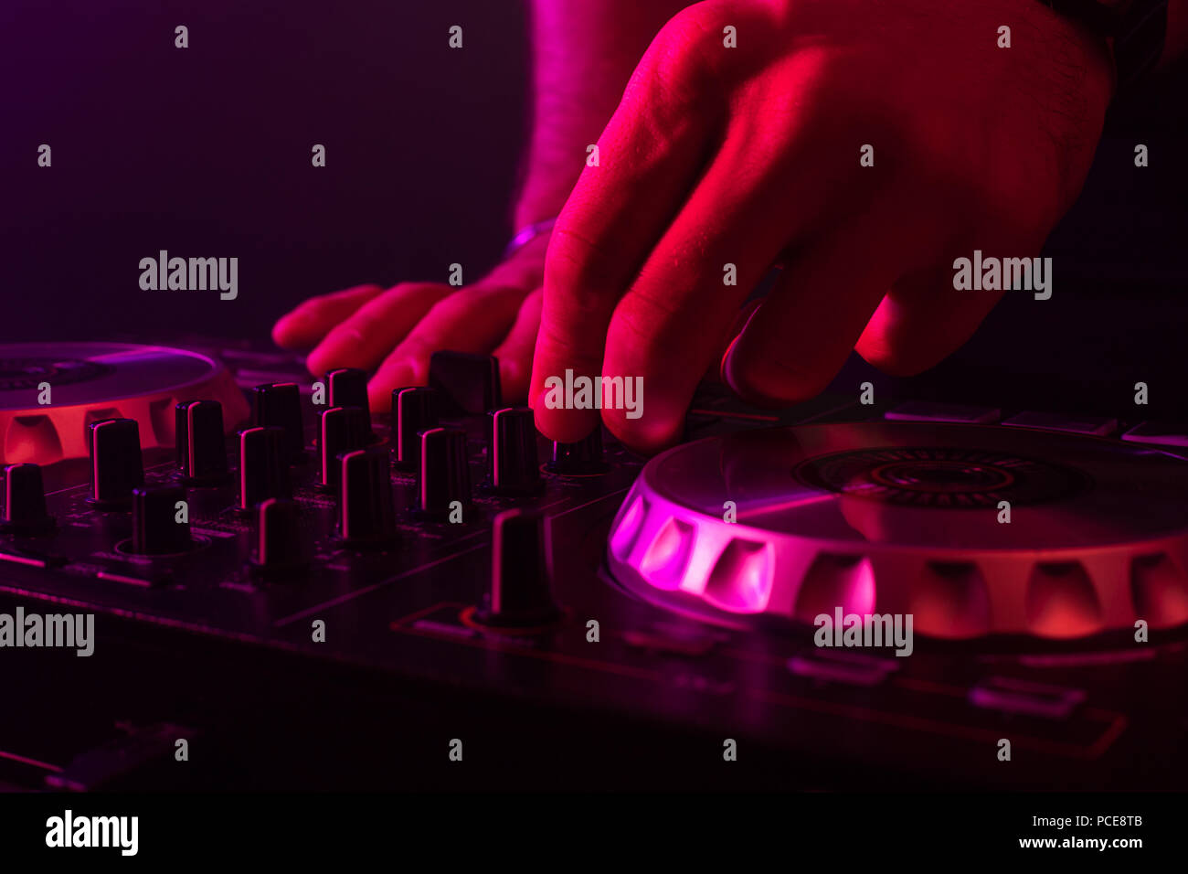 Il mixaggio DJ sul giradischi con colore effetti di luce. Soft focus sulla mano. Close-up. Divertimento, gioventù, di intrattenimento e di concetto fest Foto Stock