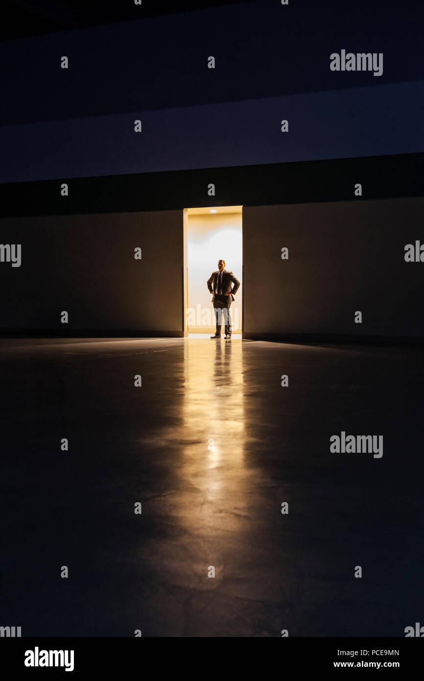 Un uomo in silhouette in piedi la porta di una grande convention center arena. Foto Stock