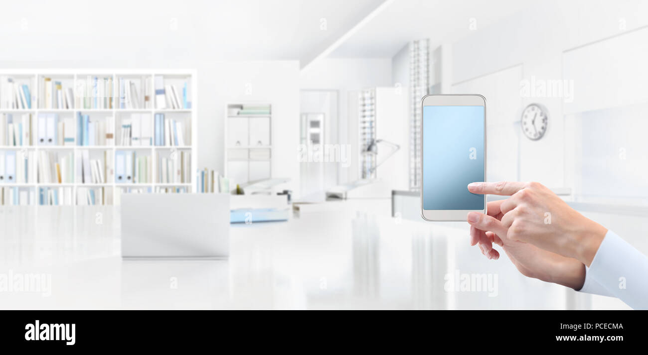 Mano con smart phone, puntare il dito sullo schermo, isolato su office interno sfondo, banner web e copiare il modello di spazio Foto Stock