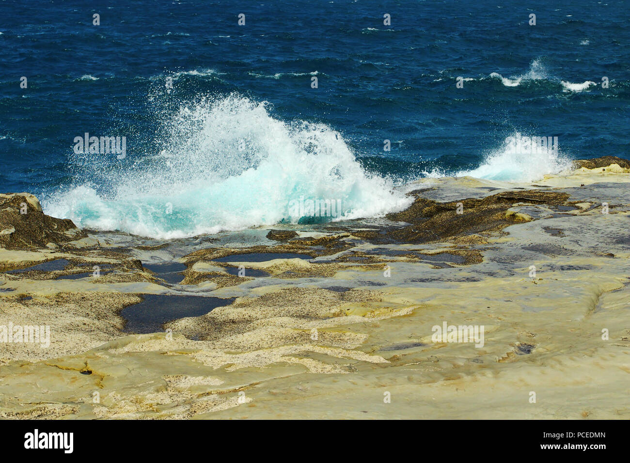 Gli spruzzi di onde sul roccioso riva del mare in Isola di Milos, Sarakiniko beach Foto Stock