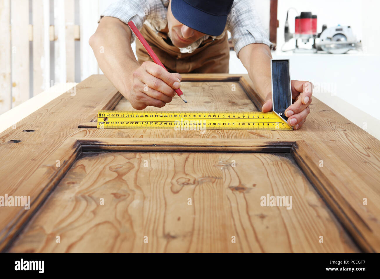 Carpenter al lavoro con le misure setsquare e matita su tavola di legno sfondo Foto Stock
