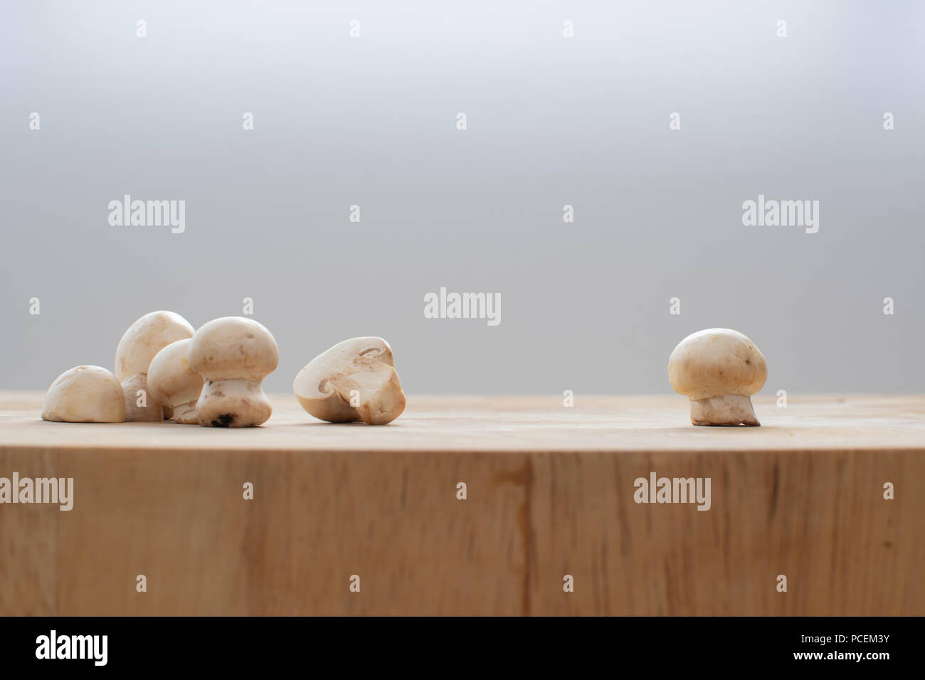 Gruppo di funghi su un tagliere di legno con un singolo fungo a destra Foto Stock