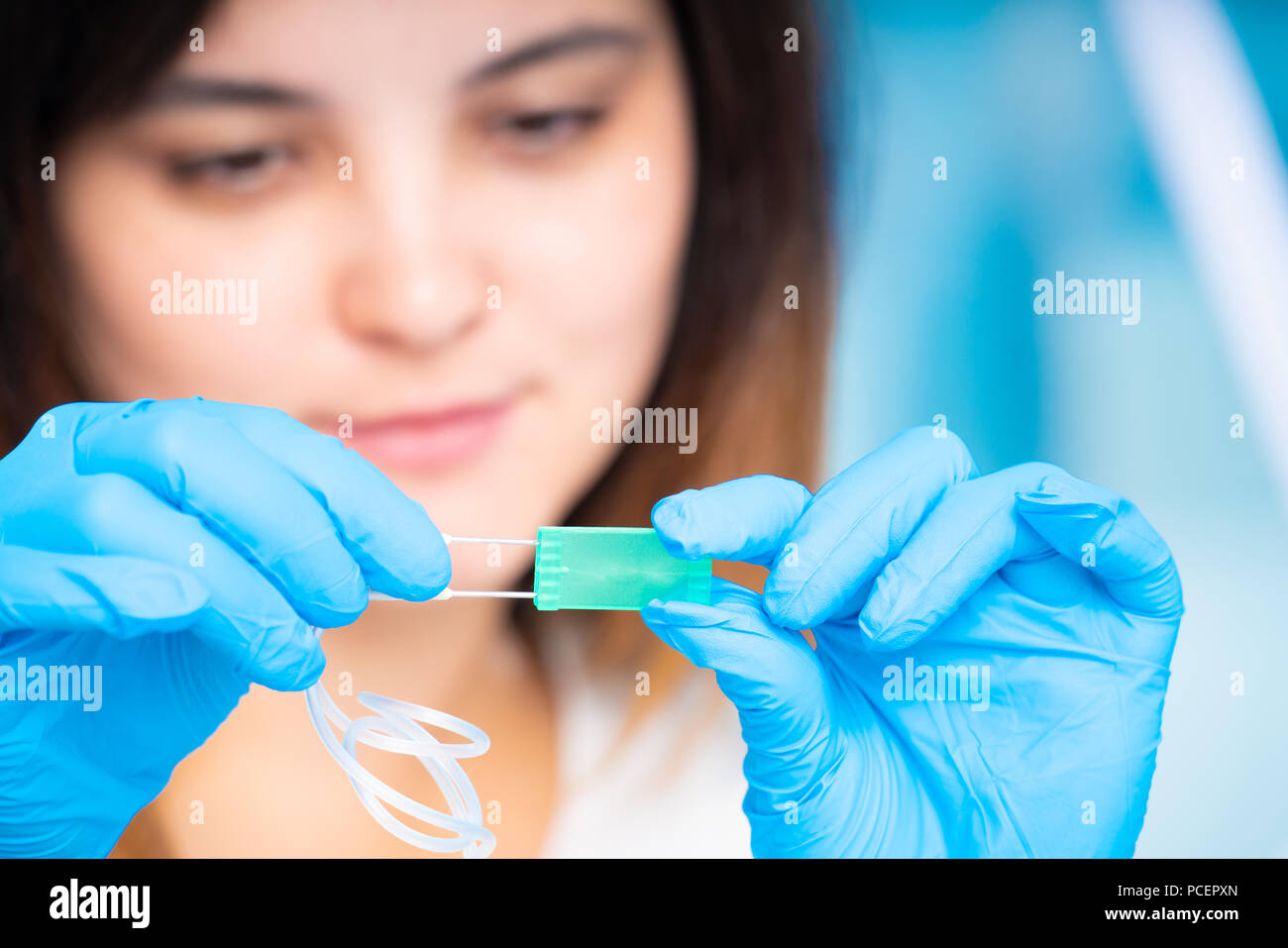 Il tecnico ragazza con dispositivo microfluidico LOC in laboratorio microbiologico Foto Stock
