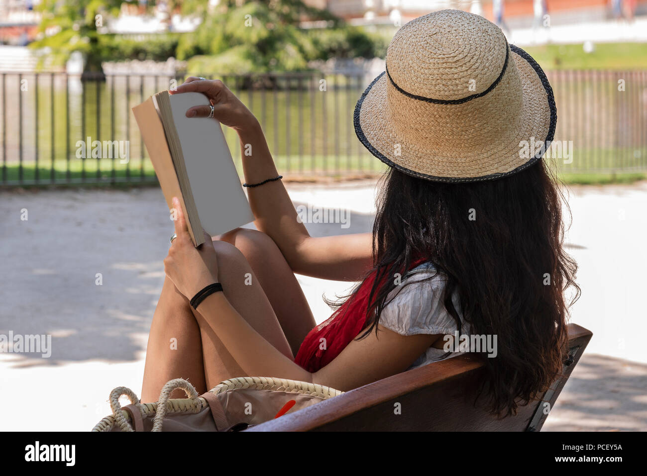 "Bella Signora giovane la lettura di un libro, seduta su una panchina nel parco. Concetto rilassata Foto Stock