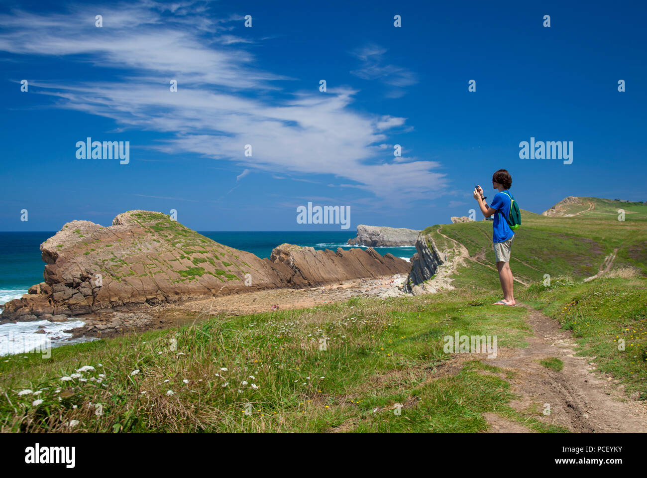 Cantabria, Costa Quebrada attorno a Playa El Madero beach, giovane uomo a scattare foto con il suo telefono cellulare Foto Stock