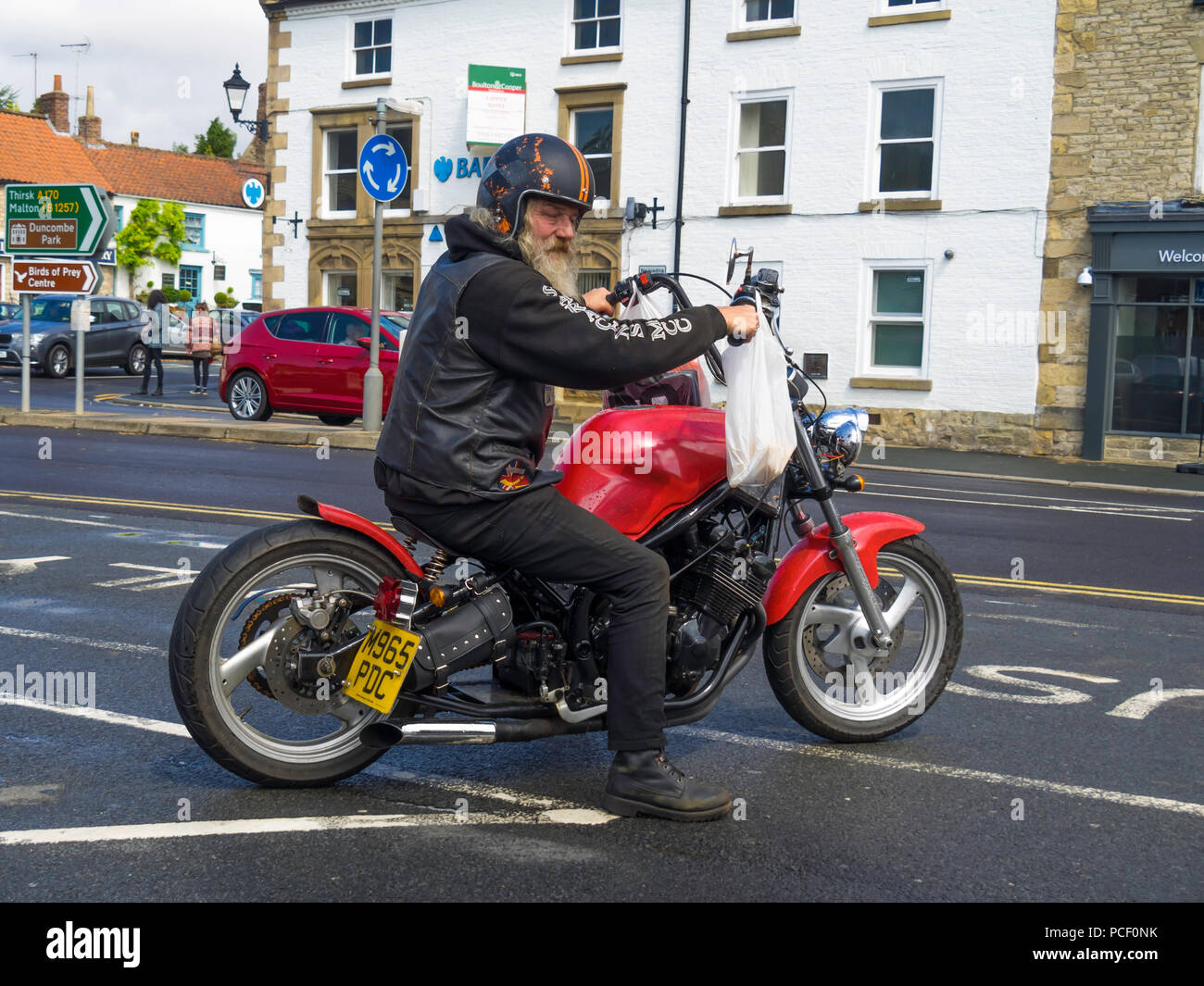 Grigio anziani barbuto motociclista sulla personalizzato costruito motociclo si fece costruire, diffondendo per tirare fuori nel traffico Foto Stock