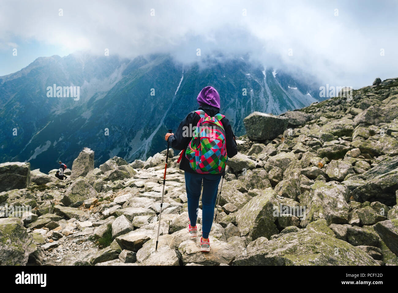 Viaggiare con lo zaino in spalla e il concetto di stile di vita. Donna viaggiatore con zaino e bastoni di tracciamento sulla cima della montagna. Il monte Rysy, Tatra, Slovacchia Foto Stock