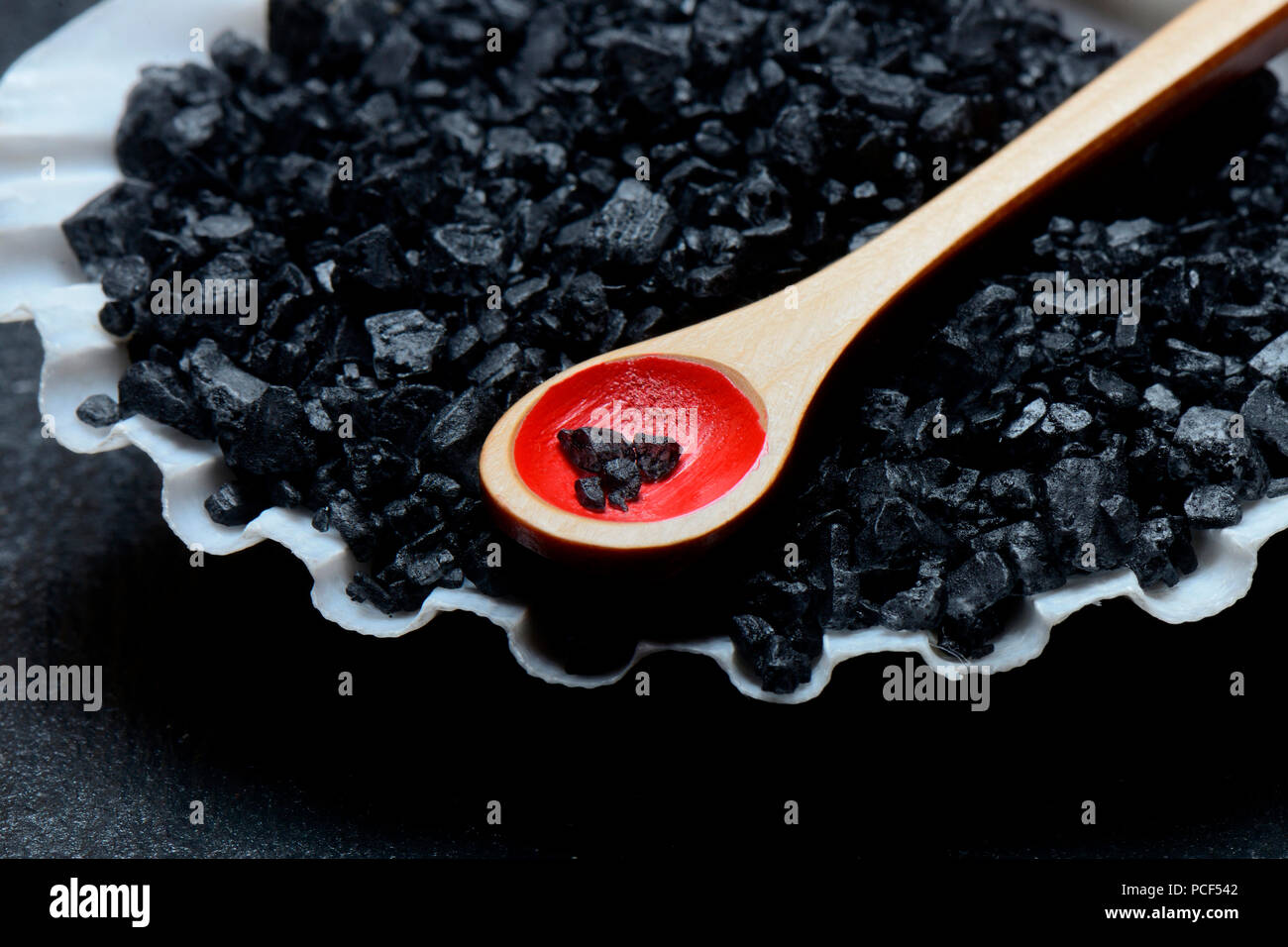 Schwarzes Hawaii-Salz in Muschelschale mit Loeffelchen, Meersalz mit Aktivkohle Foto Stock