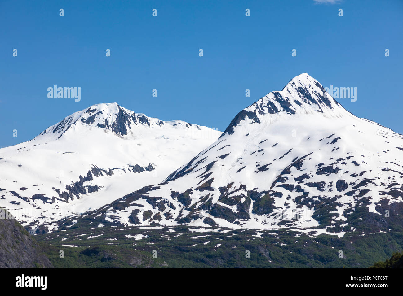 Snow capped aspre montagne rocciose sul cielo blu giorno sulla Penisola di Kenai dell Alaska Foto Stock