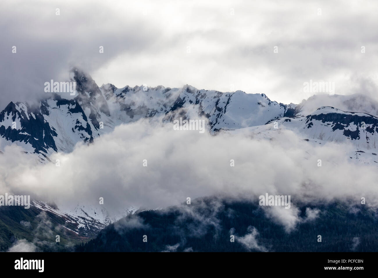 Snow capped aspre montagne rocciose in nubi sulla Penisola di Kenai dell Alaska Foto Stock