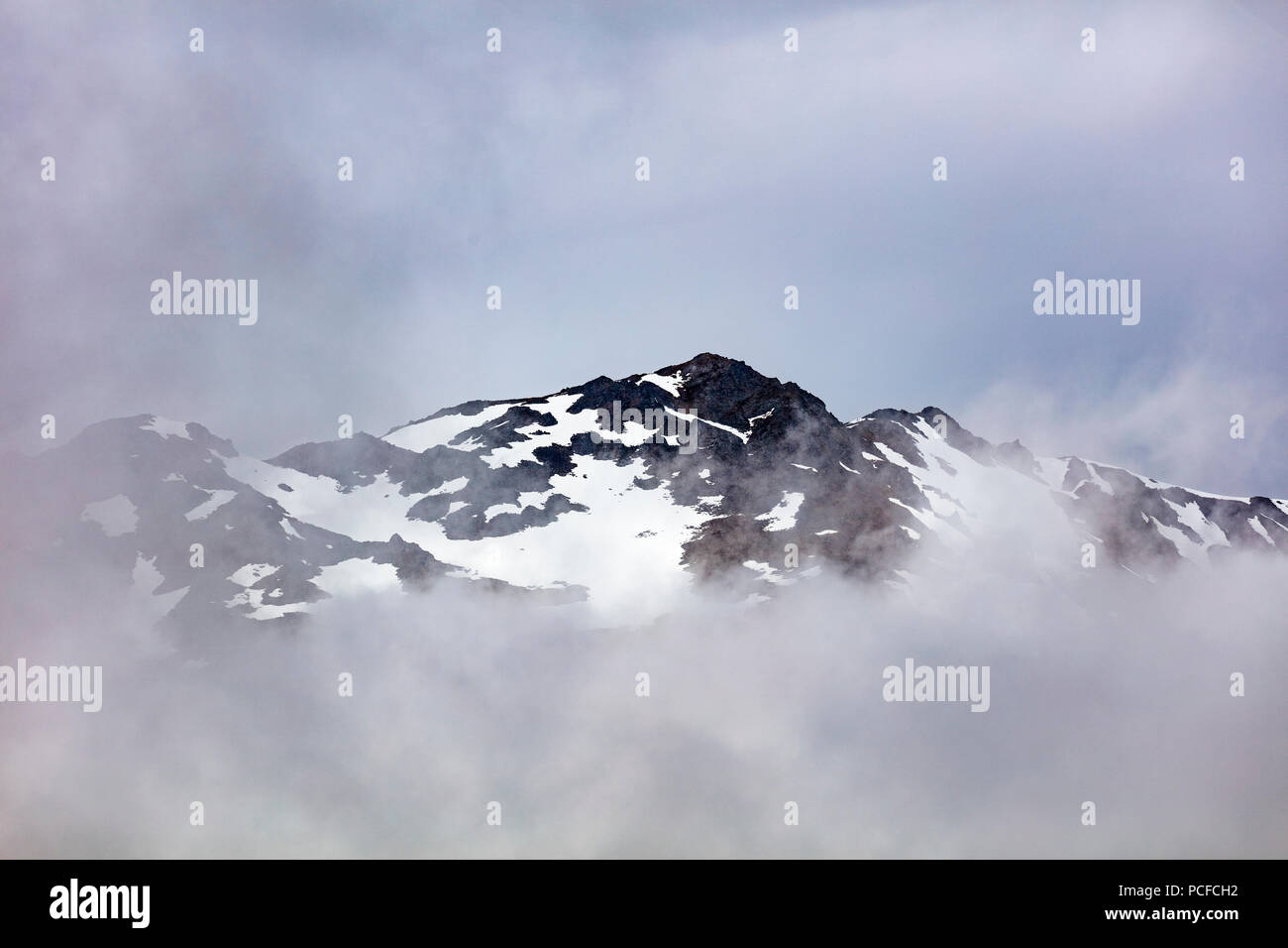 Snow capped aspre montagne rocciose in nubi sulla Penisola di Kenai dell Alaska Foto Stock