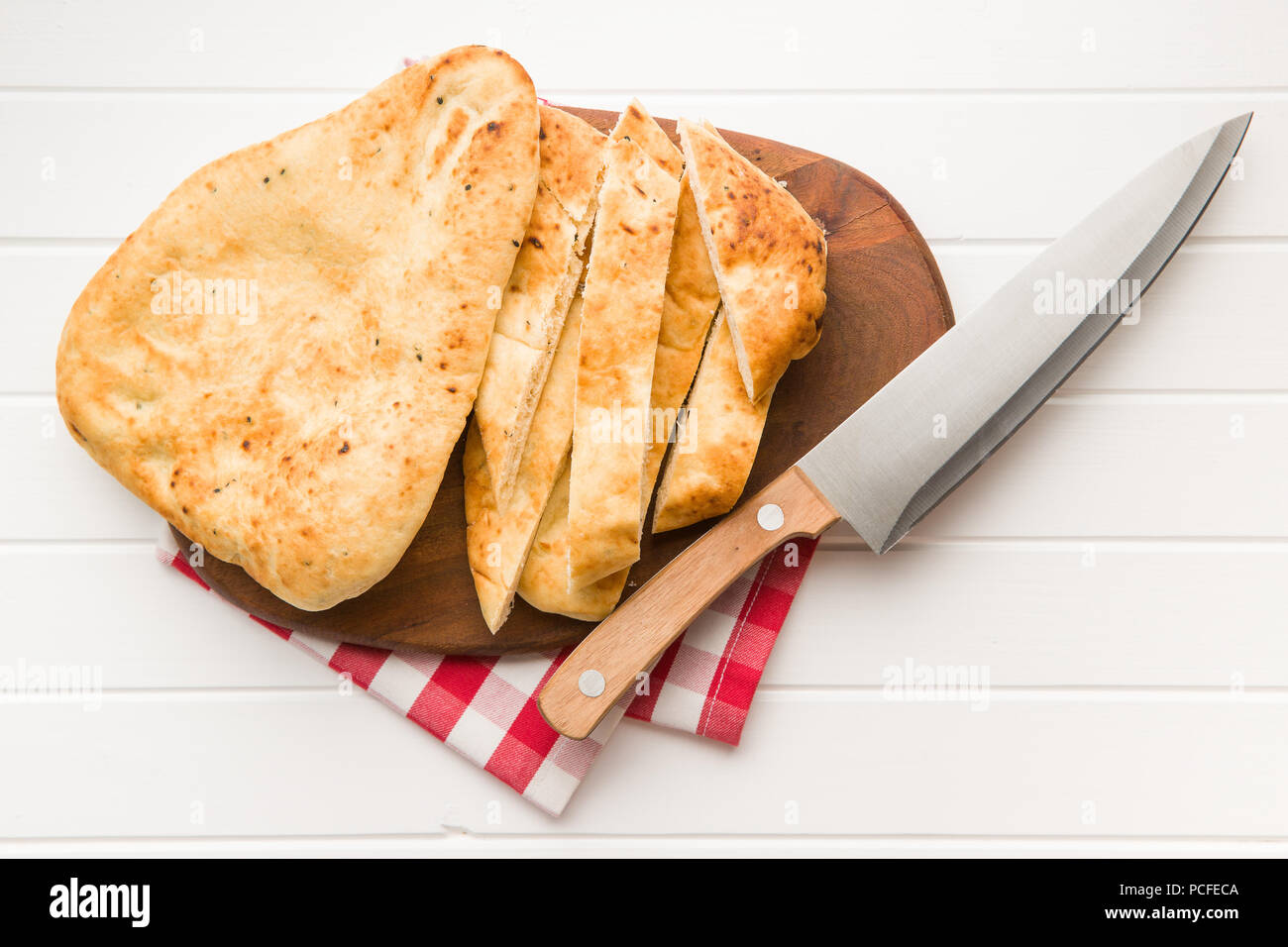 Da pane naan indiano e il coltello su bianco tavolo da cucina. Foto Stock