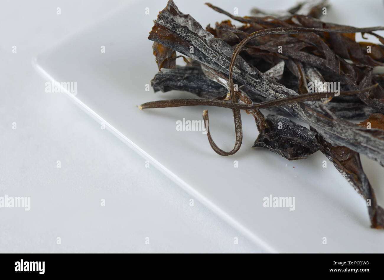 Vista dall'alto in dettaglio di secche alghe wakame:. Isolato su bianco.ricco di nutrienti vegan, materie prime sane e verdure di mare. Foto Stock