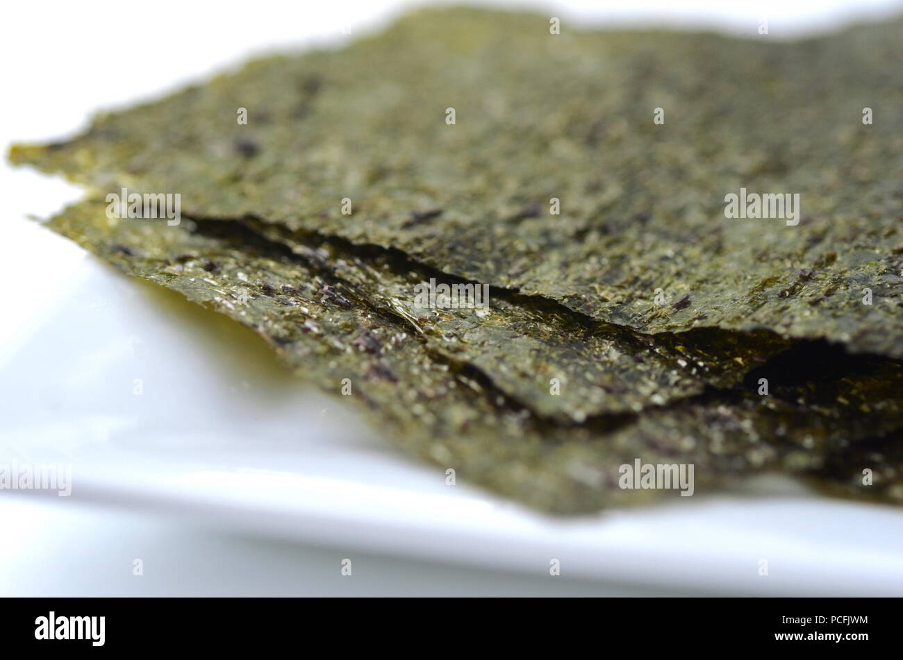 Vista dall'alto in dettaglio di alghe secche: nori. Isolato su bianco.ricco di nutrienti vegan, materie prime sane e verdure di mare. Foto Stock