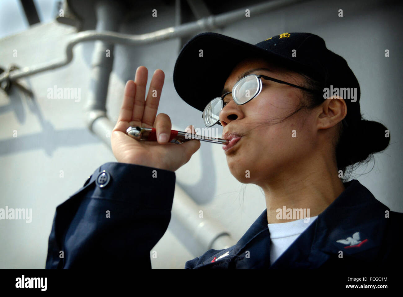 Boatswain compagno del 3° di classe Rachel Hoffman tubi un annuncio su 1MC a bordo del comando anfibio nave USS Blue Ridge praticando le sue abilità sul lato della porta di ala a ponte mentre la cottura a vapore in corso. Un boatswain tubazione dell è personalizzato da imballaggio del foro di uscita della ciotola con cera d'api per creare il passo desiderato. Blue Ridge è distribuito come negli Stati Uniti 7 ammiraglia della flotta di comandante, Expeditionary Strike gruppo 7/combinati Task Force 76. Foto Stock