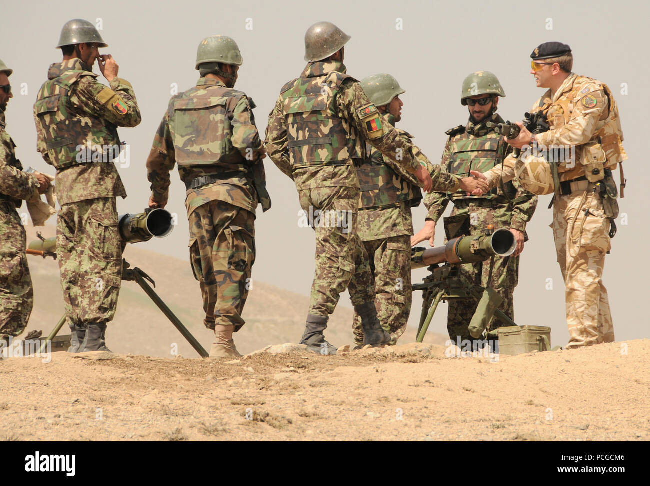 Un ufficiale dell'Esercito britannico dalla NATO Training Mission-Afghanistan si congratula con l esercito nazionale afghano soldati sul loro rendimento di tiro utilizzando il SPG-9 73 millimetro recoilless gun presso la filiale di fanteria scuola in Darulaman. La scuola insegna soldati afgani tattiche di fanteria e treni su armi fra cui malte, equipaggio servito armi e pistole recoilless. Foto Stock