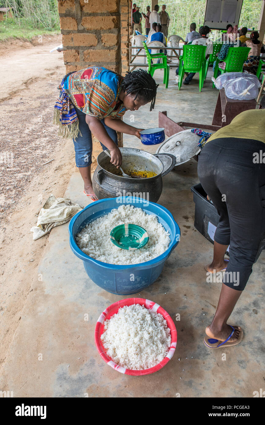 Una donna serve riso (Oryza Glaberrima) da una pentola di grandi dimensioni in Ganta, Liberia Foto Stock