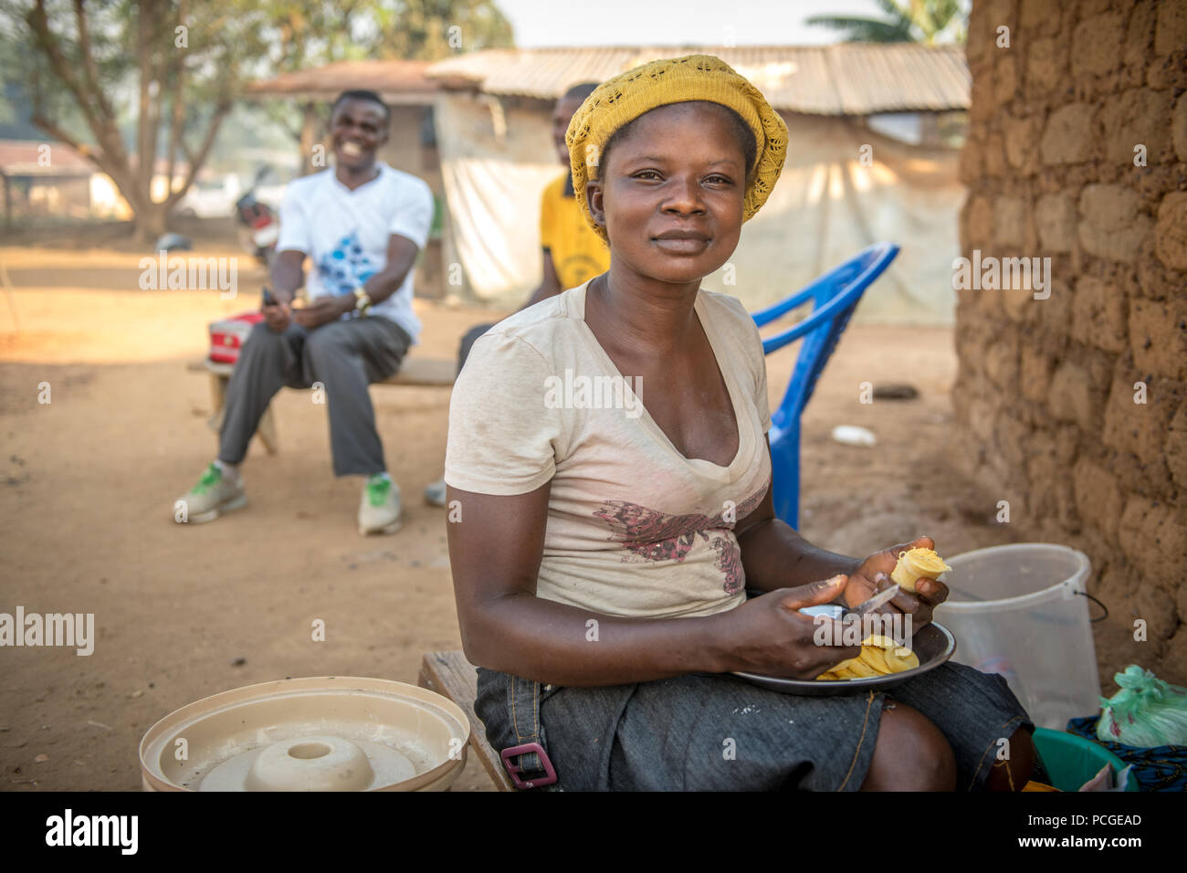 Una giovane donna taglia il cibo per un pasto in Ganta, Liberia Foto Stock