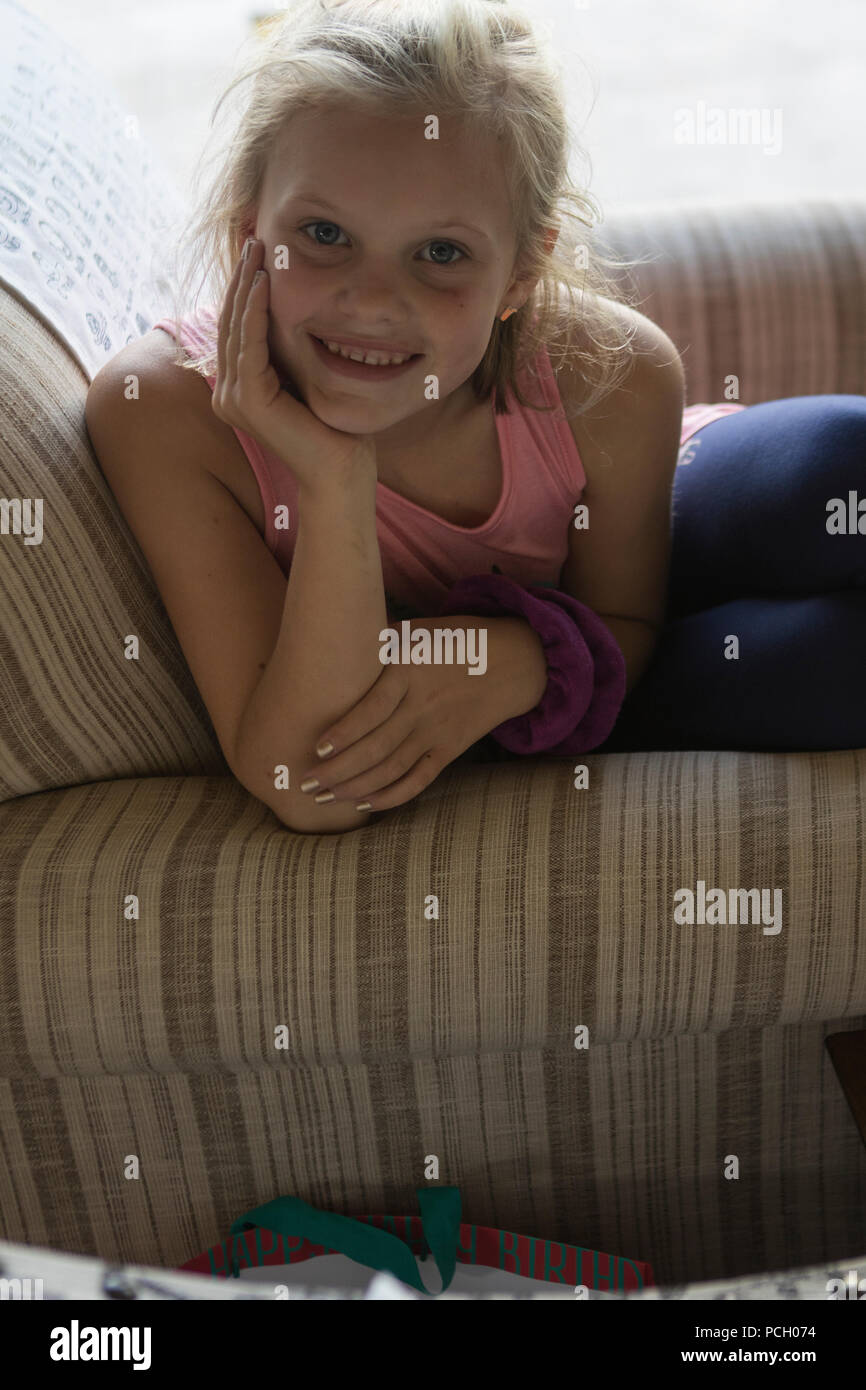 Piuttosto 8 anno vecchio bionda, guardando la fotocamera con un grande sorriso, appoggiando il mento sul lato retro illuminazione. Modello di Rilascio #113 Foto Stock