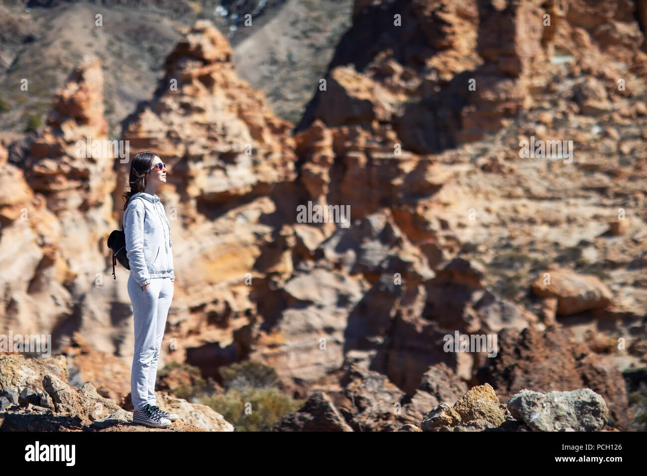 Giovane donna in piedi sul bordo della roccia godere delle montagne. Destinazione di viaggio. Parco nazionale di Tenerife, Isole Canarie, Spagna Foto Stock