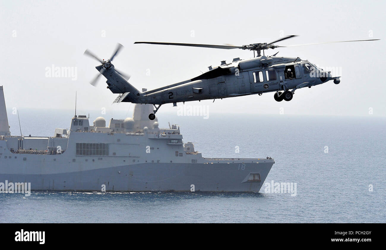 Mare Arabico (2 aprile 2012) un MH-60S Sea Hawk elicottero assegnato al Golden falchi di elicottero di mare squadrone di combattimento (HSC) 12 si prepara a terra a bordo della Nimitz-class portaerei USS Abraham Lincoln (CVN 72) come il trasporto anfibio dock nave USS New Orleans (LPD 18) transita accanto a. Abraham Lincoln è distribuito negli Stati Uniti Quinta Flotta area di responsabilità condurre le operazioni di sicurezza marittima, teatro la cooperazione in materia di sicurezza gli sforzi e le missioni di sostegno come parte dell'Operazione Enduring Freedom. Foto Stock