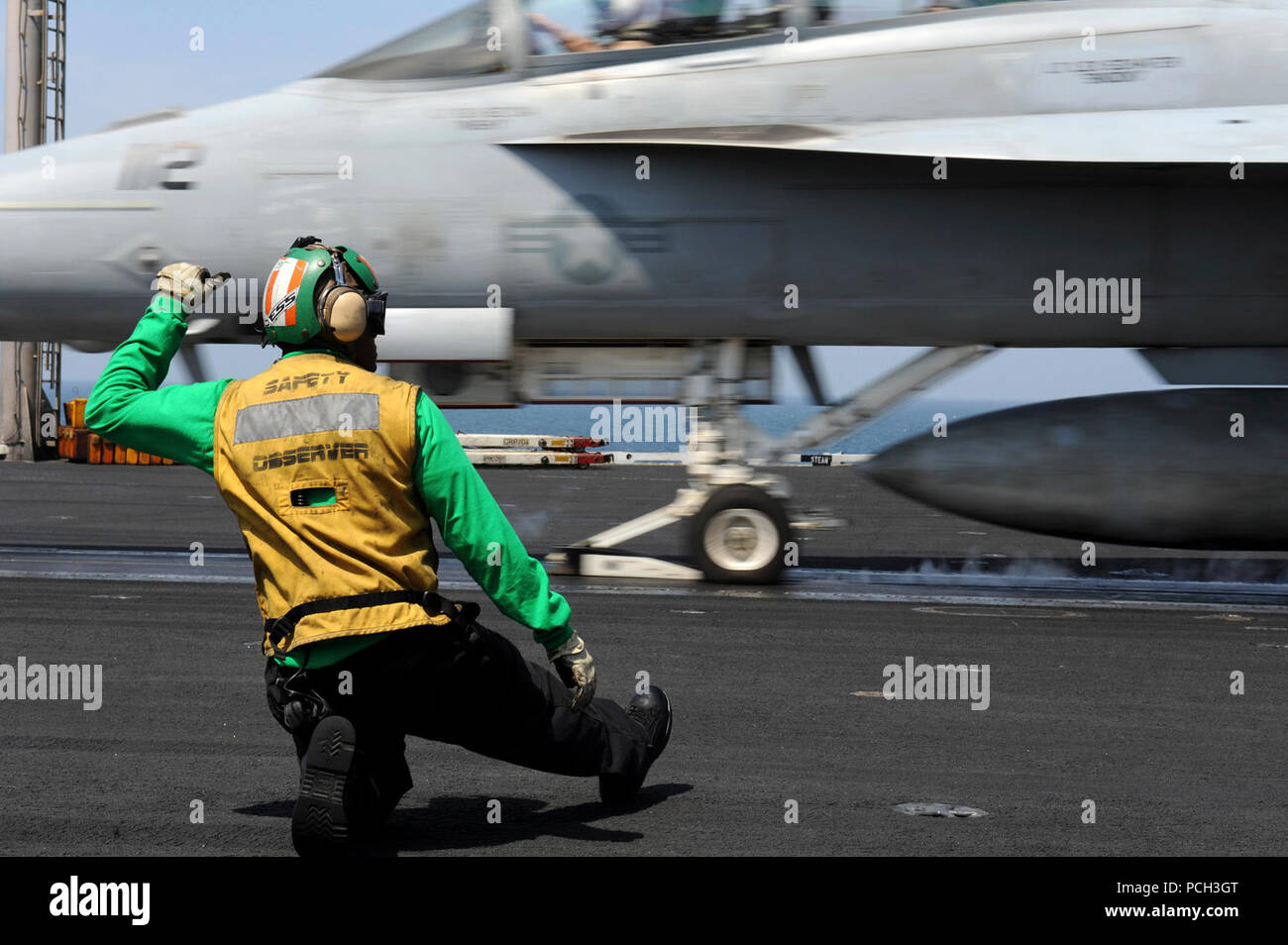 Stati Uniti 5TH FLOTTA AREA DI RESPONSABILITÀ (19 marzo 2013) di aviazione di Boatswain Mate (attrezzature) 2a classe Jerhmell segnali di Griffin per il lancio di un'F/A-18F Super Hornet dalla Black Aces di Strike Fighter Squadron (VFA) 41 sul ponte di volo a bordo della portaerei USS John C. Stennis (CVN 74). John C. Stennis Carrier Strike gruppo è distribuito negli Stati Uniti Quinta Flotta area di responsabilità condurre le operazioni di sicurezza marittima, teatro la cooperazione in materia di sicurezza gli sforzi e le missioni di sostegno per l'Operazione Enduring Freedom. Foto Stock