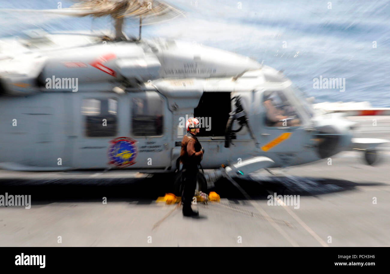 Mare (31 maggio 2012) un marinaio stand by per rimuovere tacchi e catene da un MH-60S Sea Hawk elicottero assegnato al Golden falchi di elicottero di mare squadrone di combattimento (HSC) 12 a bordo della Nimitz-class portaerei USS Abraham Lincoln (CVN 72). Abraham Lincoln è distribuito negli Stati Uniti Quinta Flotta area di responsabilità condurre le operazioni di sicurezza marittima, teatro la cooperazione in materia di sicurezza gli sforzi e le missioni di sostegno come parte dell'Operazione Enduring Freedom. Foto Stock