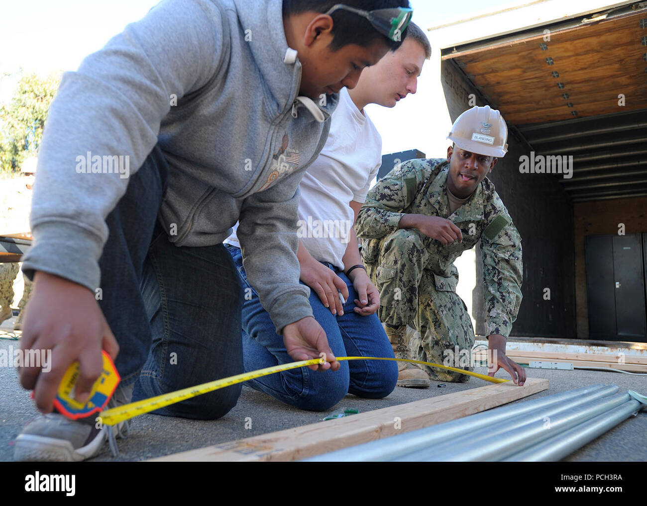 OXNARD in California (Feb. 23, 2013) Ingegneria di aiuti di prima classe Willie Blanding, assegnato alla Naval Mobile Battaglione di costruzione (NMCB) 3, mostra di Oxnard High School Junior Reserve Officer Training Corps (JROTC) agli studenti come misurare correttamente il legno. Volontari da NMCB 3's Prima Classe Petty Officer Association ha visitato la scuola per aiutare a mentor JROTC studenti e costruire delle scaffalature per un metallo grande contenitore di storage. NMCB 3 fornisce lottatori comandanti e Marina comandanti del componente con il combattimento-pronto warfighters in grado di ingegneria generale, costruzione e limited combat engineering attraverso Foto Stock