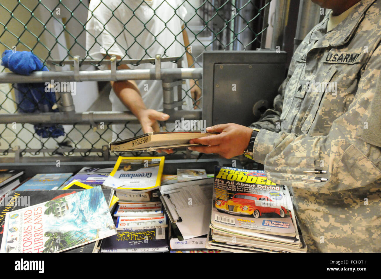 GUANTANAMO Bay a Cuba - un soldato da detenuto library mani un libro a un detenuto a Camp cinque, Feb. 16. JTF Guantanamo fornisce un sicuro, umano, legale e trasparente di cura e custodia dei detenuti, compresi quelli condannati dalla commissione militare e quelli ordinati rilasciato da un tribunale. La JTF conduce la raccolta di intelligence, analisi e diffusione per la tutela dei detenuti e il personale che lavora in JTF Guantanamo strutture e a sostegno della guerra al terrore. JTF Guantanamo fornisce il supporto per l'Ufficio di commissioni militari, di applicazione della legge e per i crimini di guerra di indagini Foto Stock