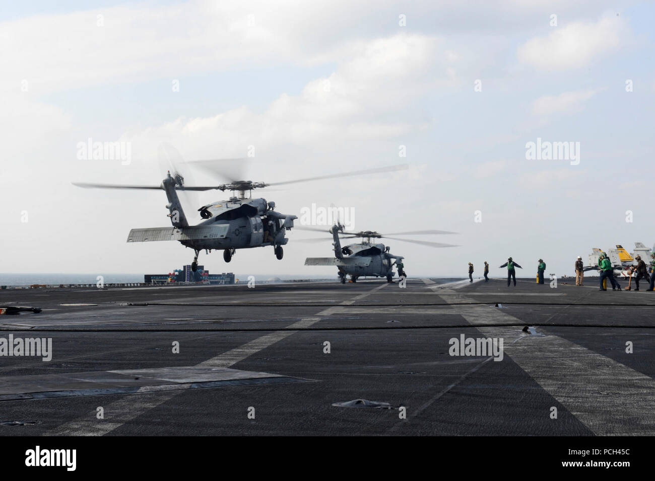 Un U.S. Navy MH-60S Seahawk elicottero, sinistra, assegnato al mare in elicottero Combat Squadron (HSC) 7, atterra sul ponte di volo della portaerei USS Harry Truman (CVN 75) Gen 12, 2014, nel Golfo Persico. L'Harry Truman è stato distribuito negli Stati Uniti Quinta Flotta area di responsabilità sostenendo gli sforzi di protezione nella regione. Foto Stock