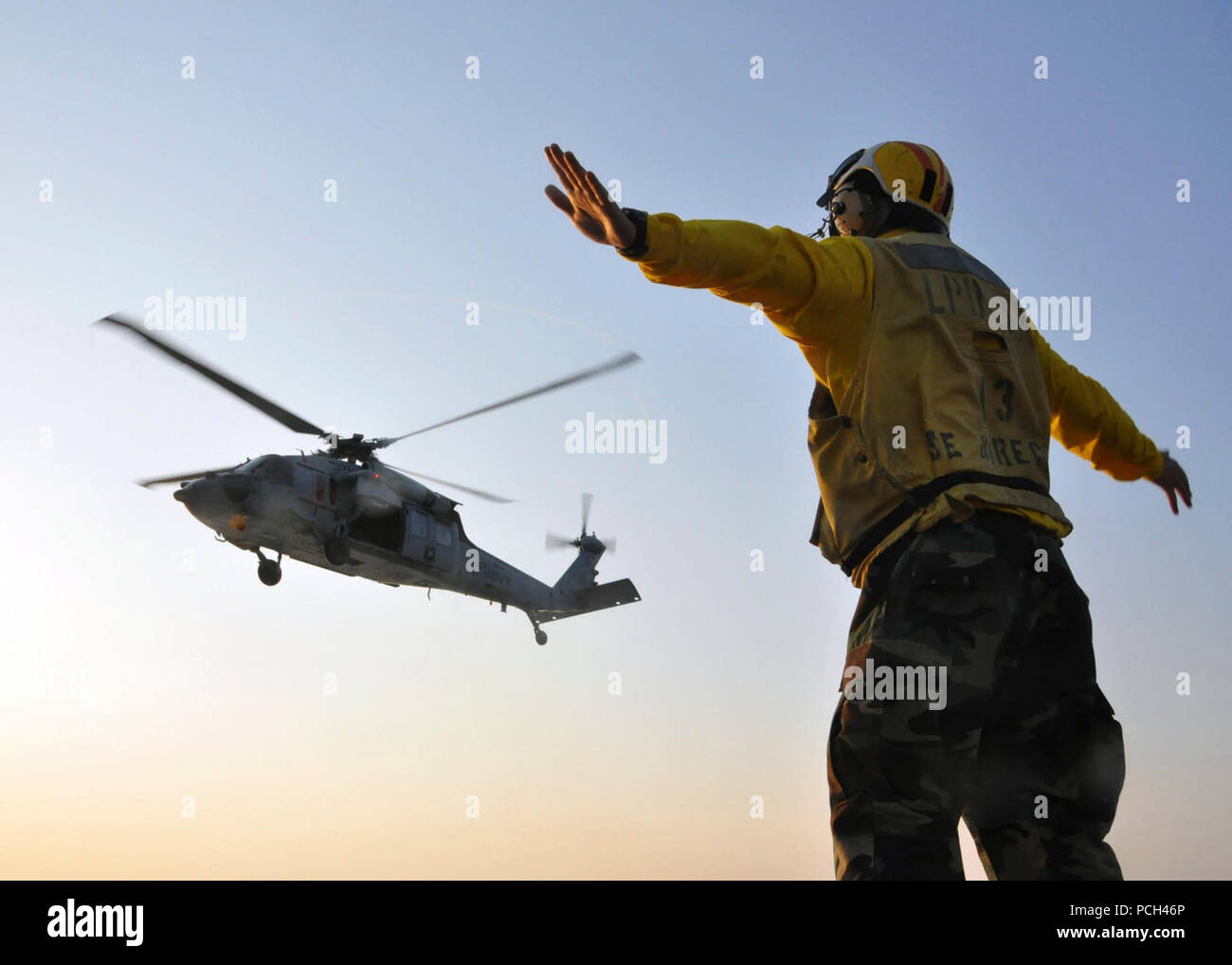 Un U.S. Sailor segnali ad un MH-60 Seahawk pilota di elicottero assegnato al mare in elicottero Combat Squadron (HSC) 2 durante le operazioni di volo a bordo di trasporto anfibio dock nave USS San Antonio (LPD 17) nell'Oceano Atlantico il 10 giugno 2011. San Antonio stava conducendo prova in mare evoluzioni. Foto Stock
