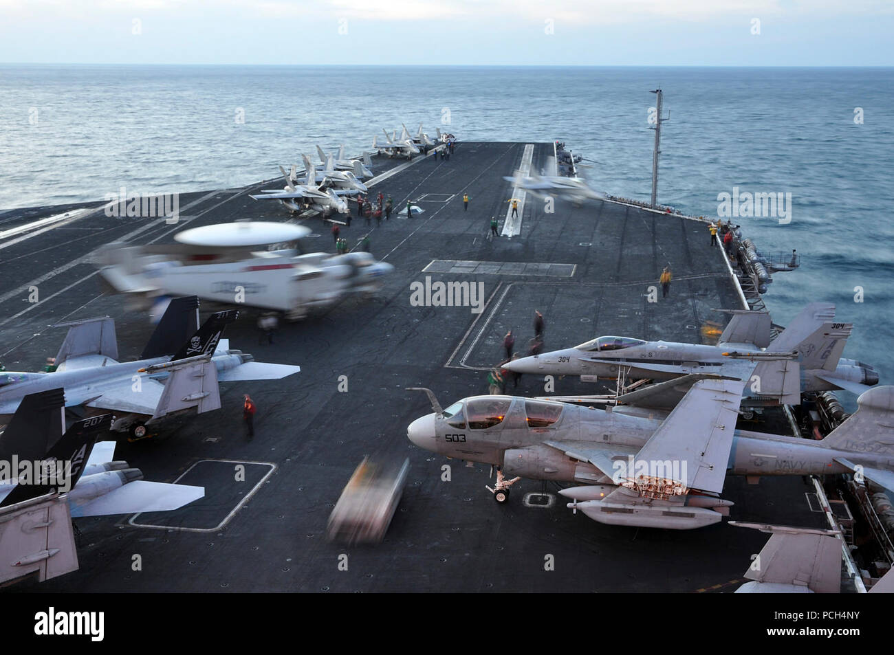 Stati Uniti 5TH FLOTTA AREA DI RESPONSABILITÀ (nov. 17, 2012) gli aeromobili e il personale si muovono attorno al ponte di volo serale come operazioni di volo iniziano a bordo della Nimitz-class portaerei USS Dwight D. Eisenhower CVN (69). Dwight D. Eisenhower è distribuito negli Stati Uniti Quinta Flotta area di responsabilità condurre le operazioni di sicurezza marittima, teatro di sicurezza gli sforzi di cooperazione e sostegno la missione come parte dell'Operazione Enduring Freedom. Foto Stock