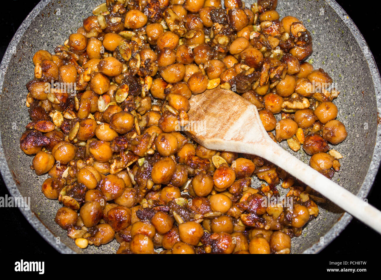 La tostatura gustoso croccante di ceci in una padella con un cucchiaio di legno Foto Stock