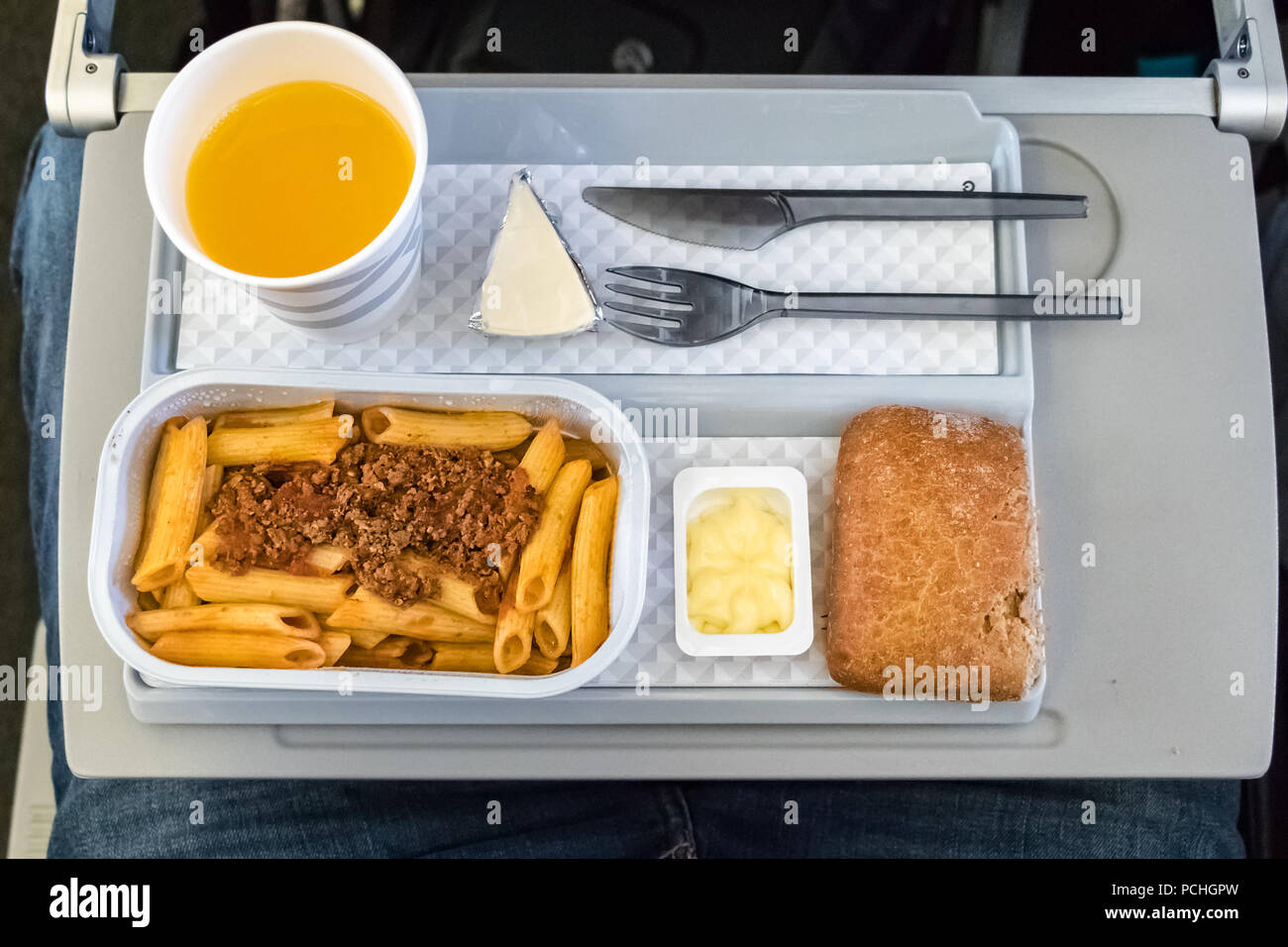 Un volo in pasto - pranzo con succo di arancia e la pasta a bordo della classe economica di una compagnia aerea tedesca.vista dall'alto. Foto Stock