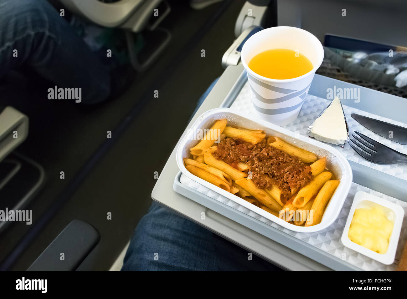 Un volo in pasto - pranzo con succo di arancia e la pasta a bordo della classe economica di una compagnia aerea tedesca.vista dall'alto. Foto Stock